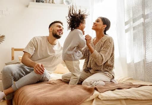 couple and young child playing on a bed